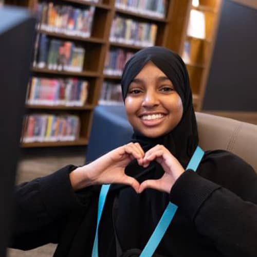 women sitting down with her hands shaped like a heart