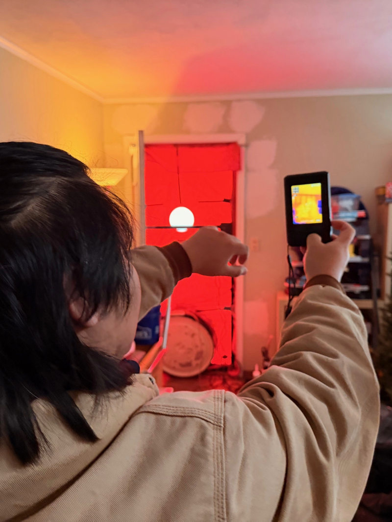 Our partner at Center for Energy and Environment or Home Energy Squad using a sensor to detect cold spots in a client’s home.