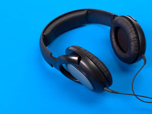 A pair of black headphones against a bright blue background.