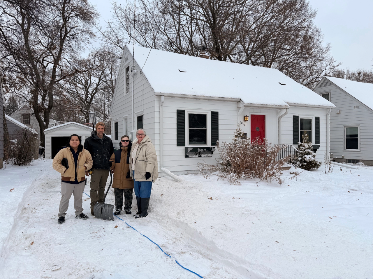Lori Mueller, a client from our weatherization pilot project, in front of her home with her son and our weatherization contractors.