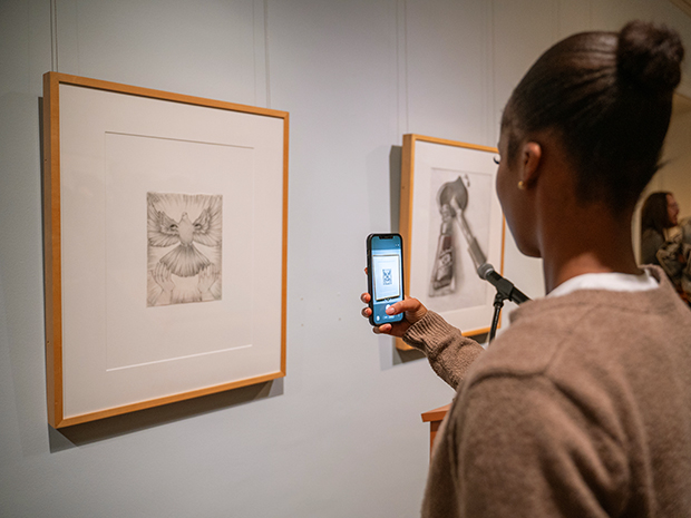 An event guest takes a picture of student artwork.