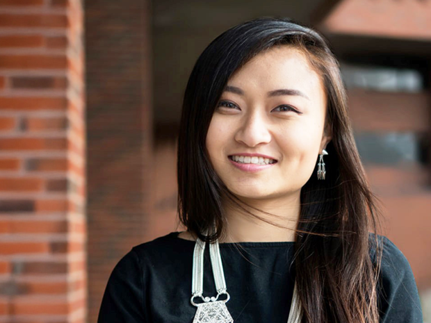 Elevate Hennepin's business navigator, MayPa Yang, stands in front of a brick building.