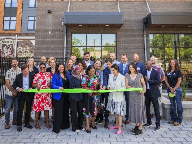 A group of people cut a ribbon at a building grand opening.