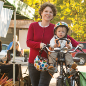 A mother holding her child on a bike. 