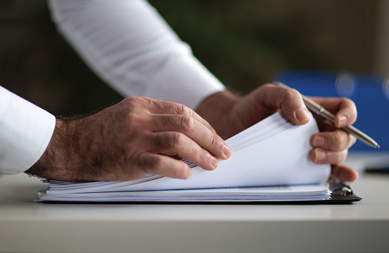 mans hands on paper with a pen