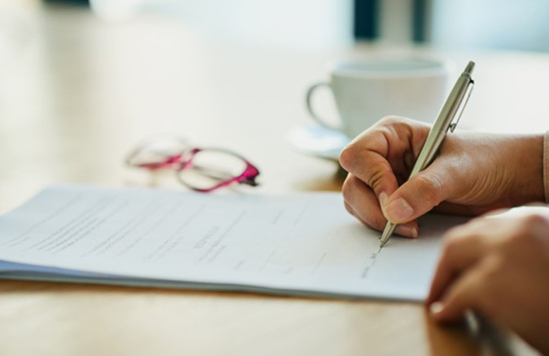 person hands signing a paper