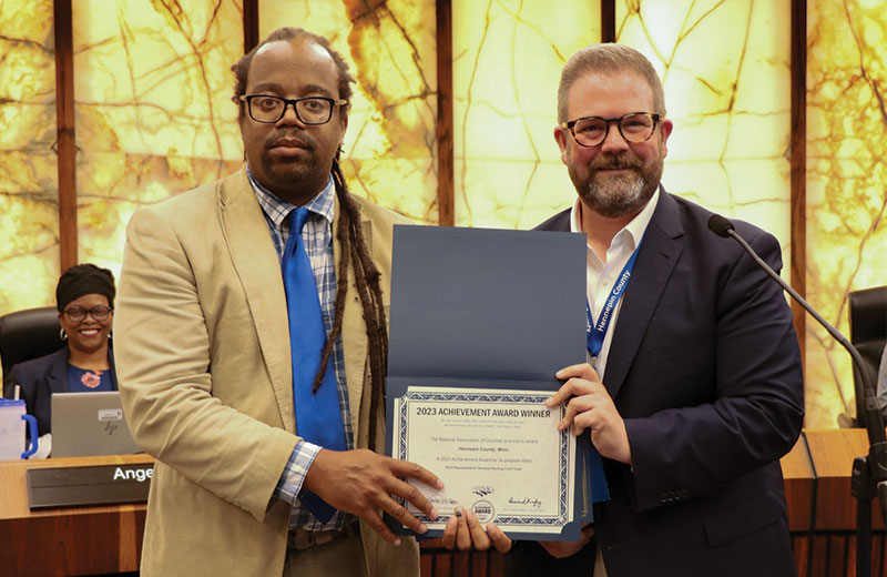 man receiving an award from a commissioner
