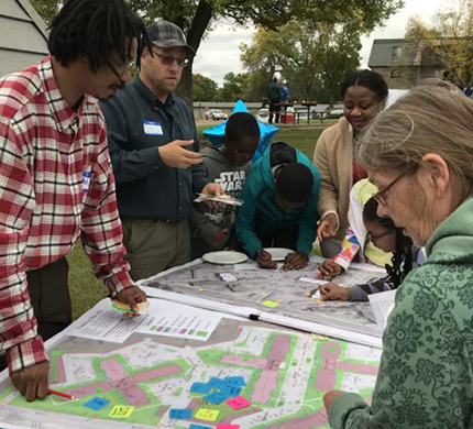 Community members gathered around a table giving feedback on a design
