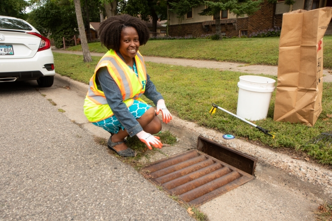 Woman kneeling next to storm drain