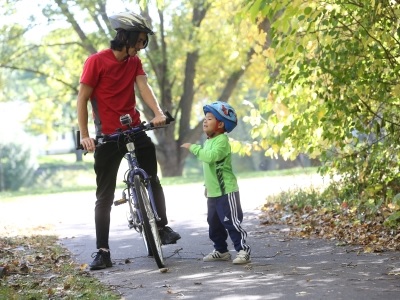 Father on a bike talking to young son.