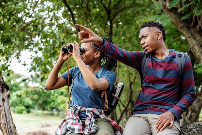 Man pointing while woman looks through binoculars