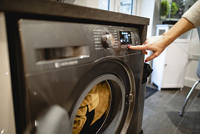A close-up shot of a woman pressing a button on her washing machine.