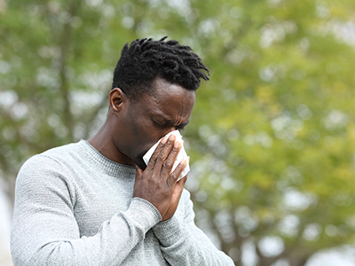 Man blowing his nose outside