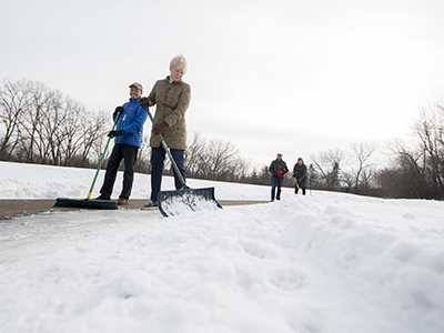Two people shoveling a sidewalk