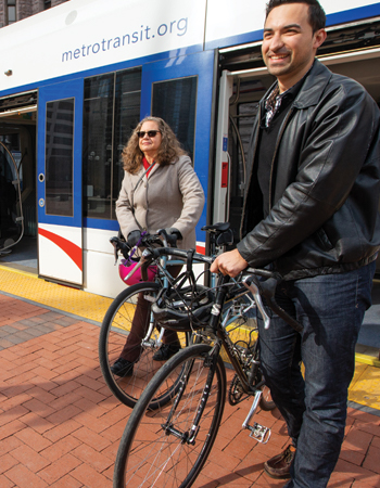 man and woman biking near a llight rail train downtown Minneapolis