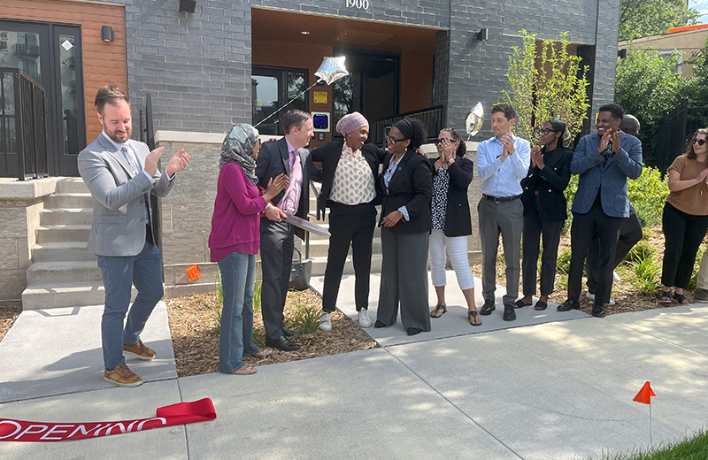 people clapping in front of building after ribbon cutting