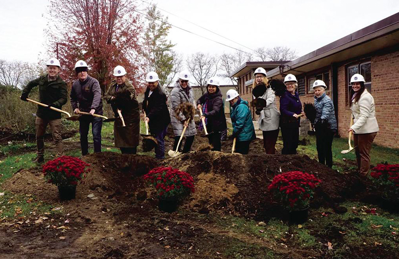 group of people shoveling dirt for groundbreaking