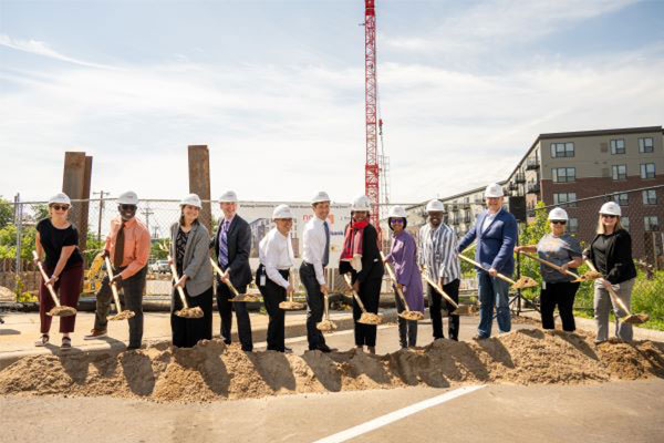 people outside shoveling dirt for the groundbreaking